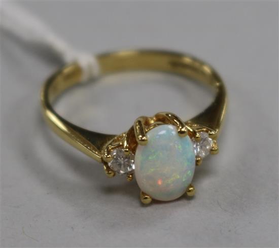An opal and diamond three-stone ring, the opal flanked by two brilliants, 18ct gold setting, size O.